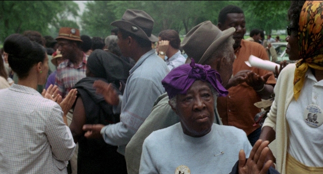 Wide shot frame from Medium Cool — standing, dialogue, hat
