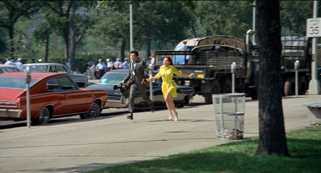 Wide shot frame from Medium Cool — walking, street, car