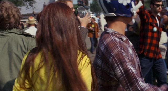 Wide shot frame from Medium Cool — standing, street, hat
