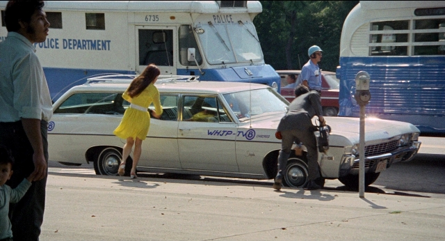Wide shot frame from Medium Cool — standing, street, car