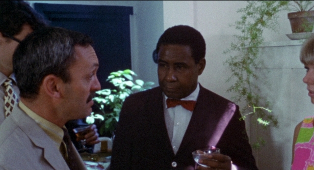 Wide shot frame from Medium Cool — room, dialogue, suit
