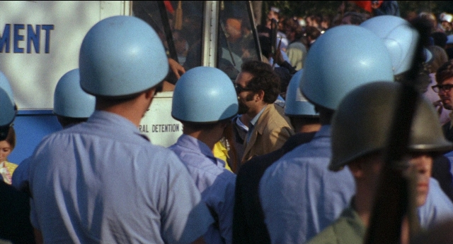 Wide shot frame from Medium Cool — standing, dialogue, street
