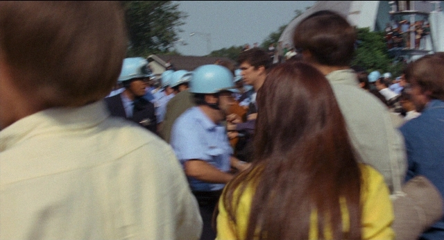 Wide shot frame from Medium Cool — dialogue, shirt, hair