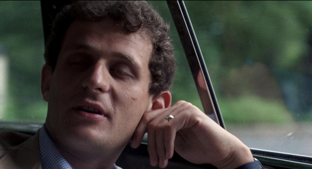 Close-up frame from Medium Cool — car, hand, suit