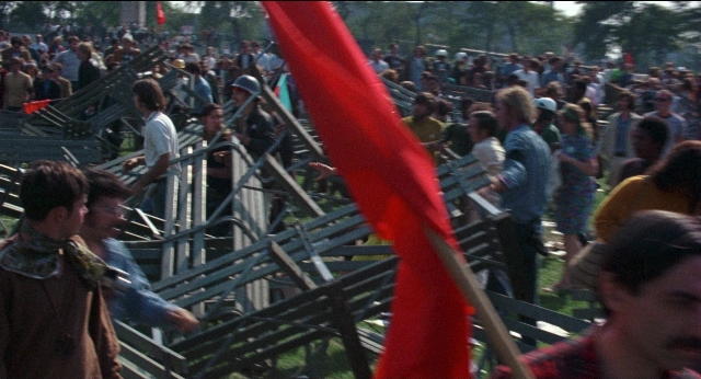 Wide shot frame from Medium Cool — flag, person, human face