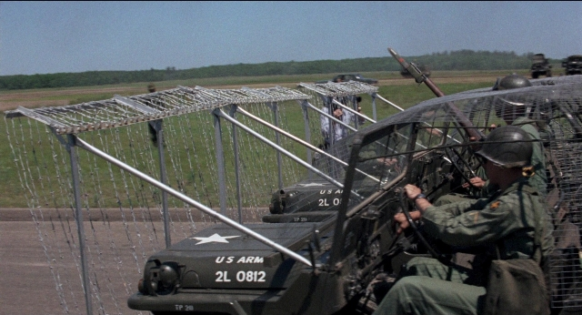 Wide shot frame from Medium Cool — sitting, gun, airplane