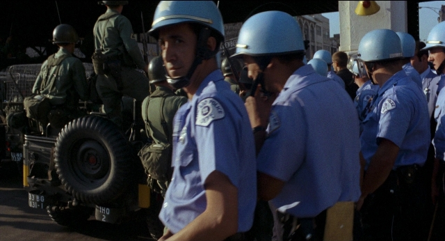 Wide shot frame from Medium Cool — standing, dialogue, street