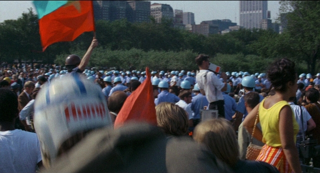 Wide shot frame from Medium Cool — standing, flag, person