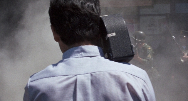 Frame from Medium Cool — standing, shirt, smoke