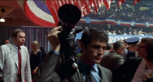 Wide shot frame from Medium Cool — room, flag, suit