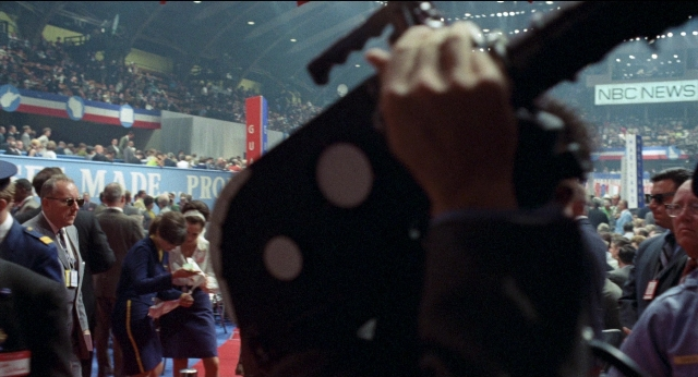 Wide shot frame from Medium Cool — hand, suit, tie