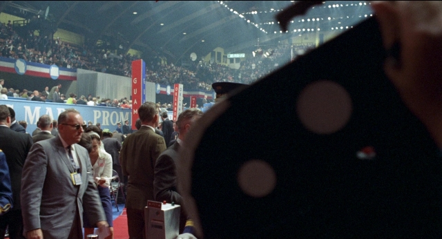 Wide shot frame from Medium Cool — walking, dialogue, suit