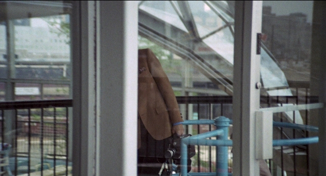 Frame from Medium Cool — standing, hand, glass