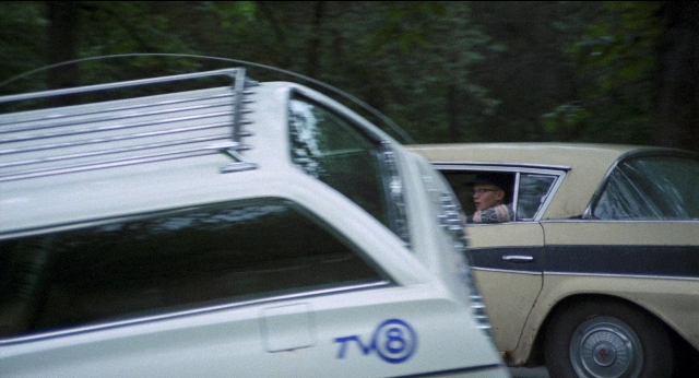 Frame from Medium Cool — street, hat, car
