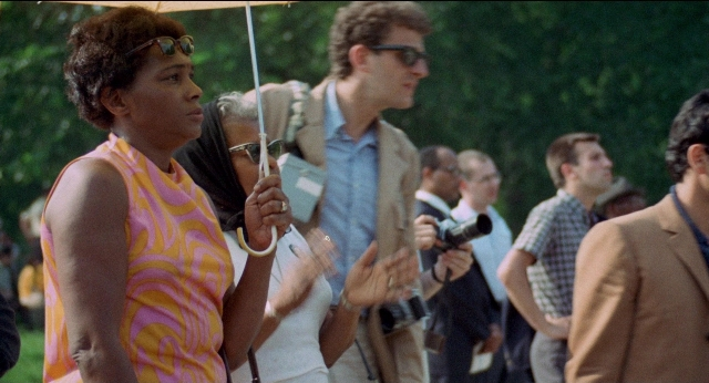 Wide shot frame from Medium Cool — standing, dialogue, hand