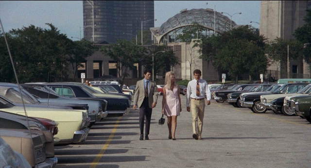 Wide shot frame from Medium Cool — walking, car, suit