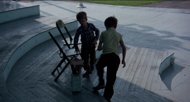 Wide shot frame from Medium Cool — walking, table, street