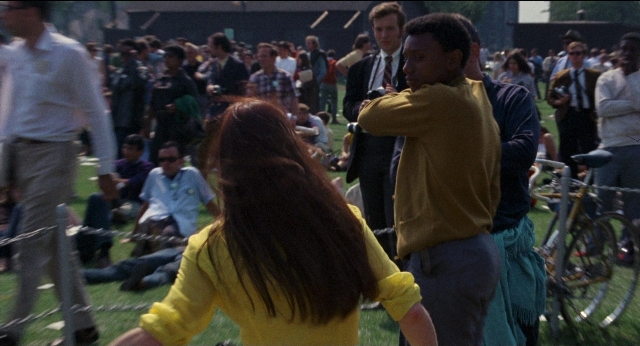 Wide shot frame from Medium Cool — sitting, standing, dialogue