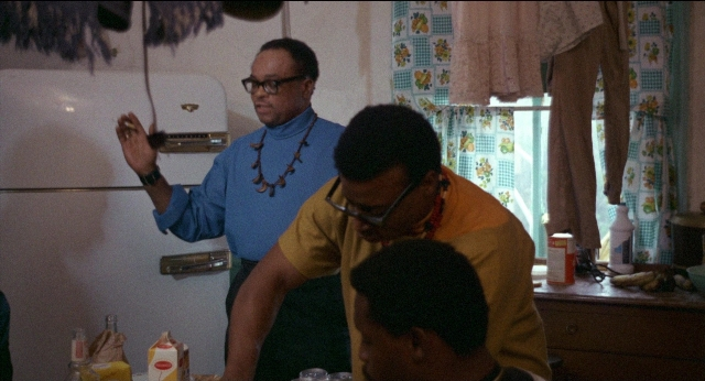 Wide shot frame from Medium Cool — standing, kitchen, hand