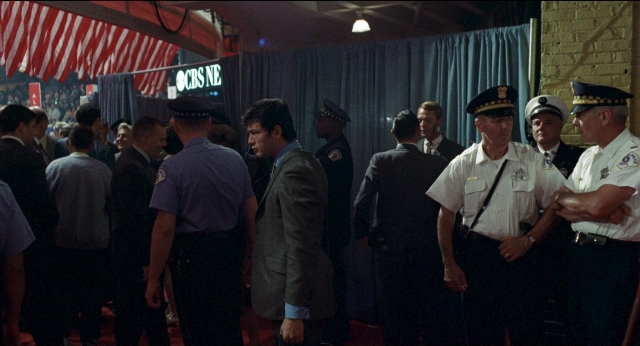 Wide shot frame from Medium Cool — standing, room, dialogue