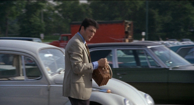 Wide shot frame from Medium Cool — standing, car, hand