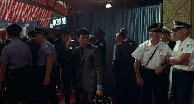 Wide shot frame from Medium Cool — standing, room, dialogue