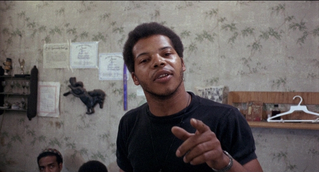 Frame from Medium Cool — standing, room, hand