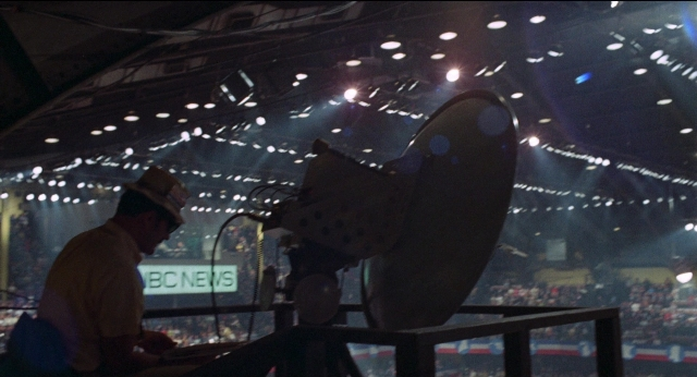 Wide shot frame from Medium Cool — sitting, hat, night