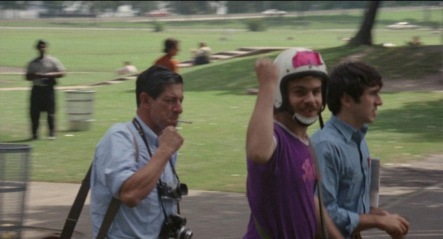 Wide shot frame from Medium Cool — sitting, standing, walking