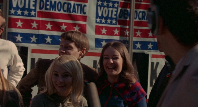 Wide shot frame from Medium Cool — standing, dialogue, flag