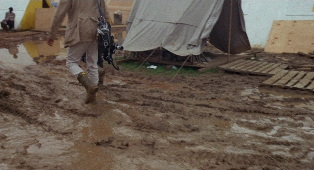 Frame from Medium Cool — walking, tent, water