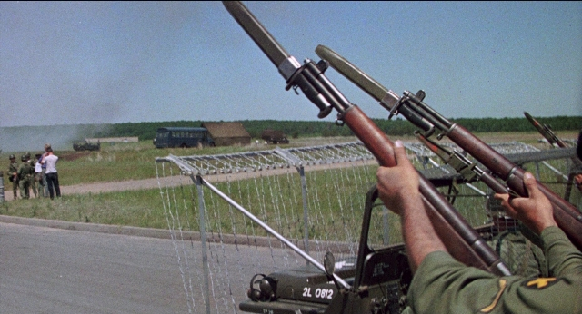 Wide shot frame from Medium Cool — car, gun, person
