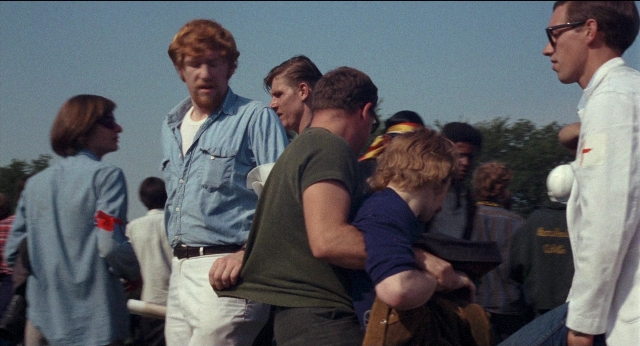 Wide shot frame from Medium Cool — standing, dialogue, hand