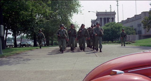 Wide shot frame from Medium Cool — walking, street, car