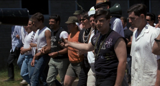 Wide shot frame from Medium Cool — walking, dialogue, hat