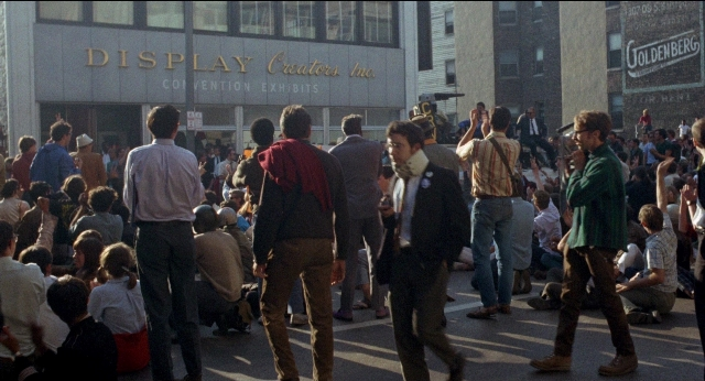 Wide shot frame from Medium Cool — sitting, standing, walking