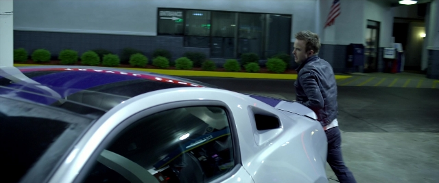 Wide shot frame from Need for Speed — standing, car, hand