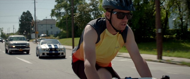 Wide shot frame from Need for Speed — street, hat, car