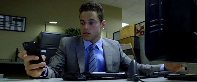 Wide shot frame from Need for Speed — sitting, phone, suit