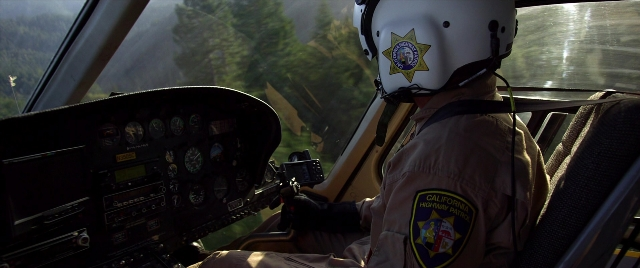 Wide shot frame from Need for Speed — sitting, hat, car