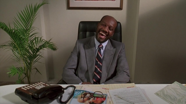 Frame from Cool Runnings — sitting, book, room