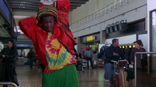 Wide shot frame from Cool Runnings — walking, tie, bag