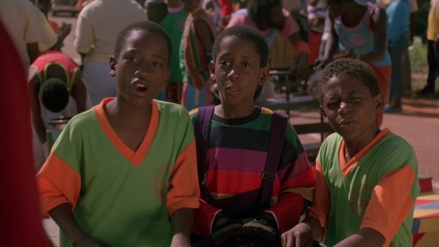 Wide shot frame from Cool Runnings — sitting, walking, street