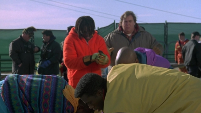 Wide shot frame from Cool Runnings — hand, person, human face