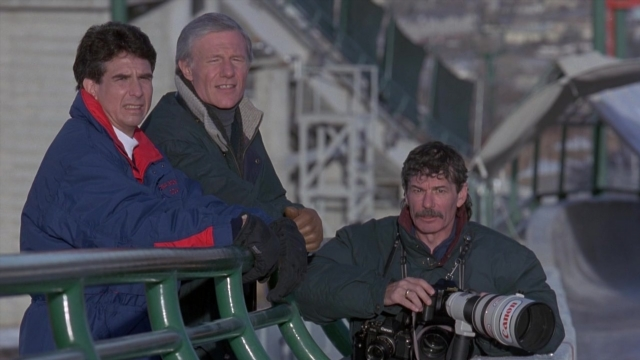Wide shot frame from Cool Runnings — sitting, camera, snow