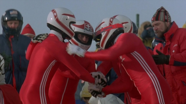 Wide shot frame from Cool Runnings — standing, hat, coat