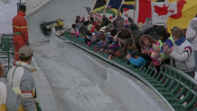 Wide shot frame from Cool Runnings — standing, hat, flag