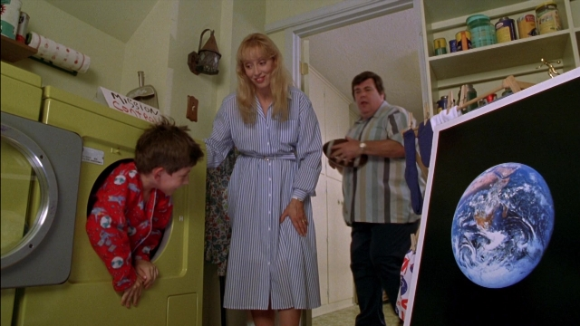 Wide shot frame from Rocketman — standing, dialogue, kitchen