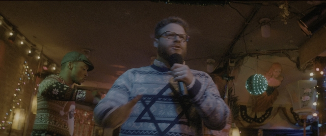 Wide shot frame from The Night Before — standing, dialogue, hat