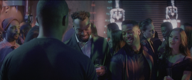 Wide shot frame from The Night Before — room, dialogue, hand